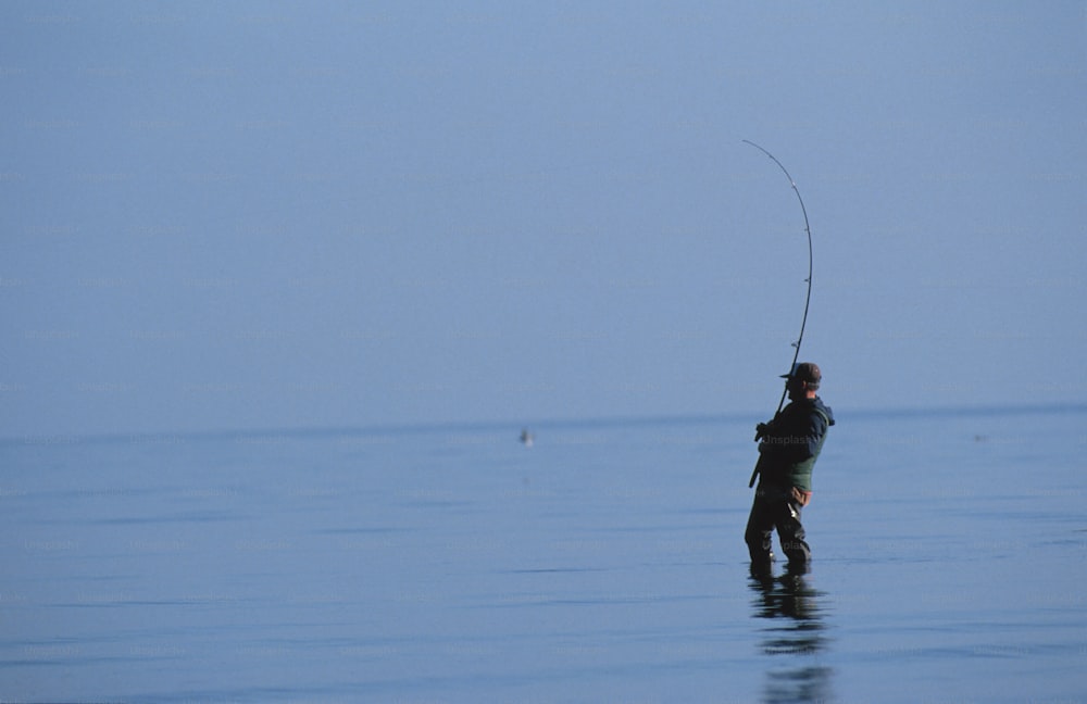 a man standing in the water with a fishing rod