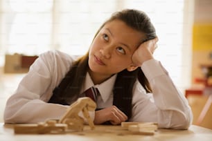 a young girl sitting at a table with a toy horse