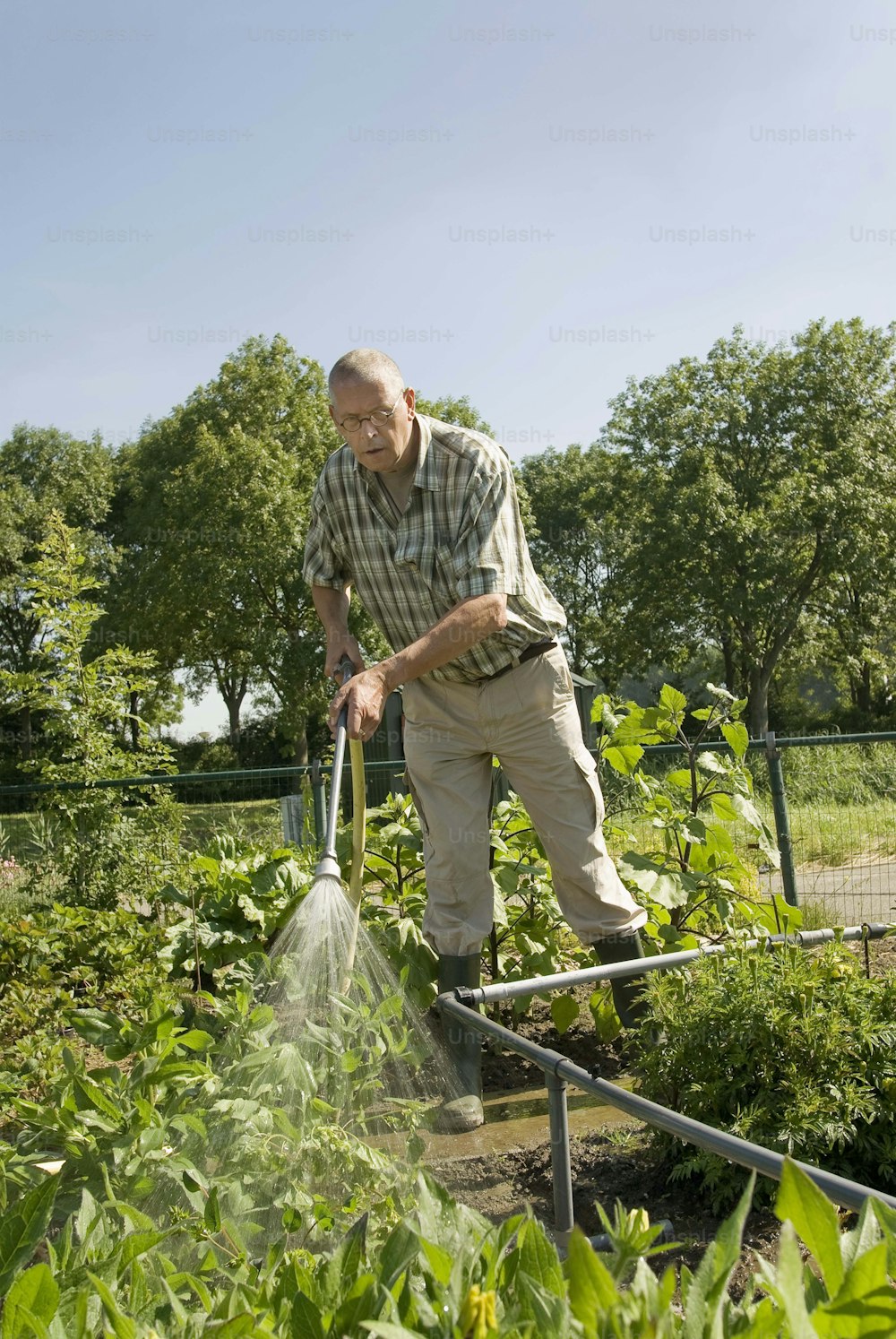 a man watering his garden with a garden hose