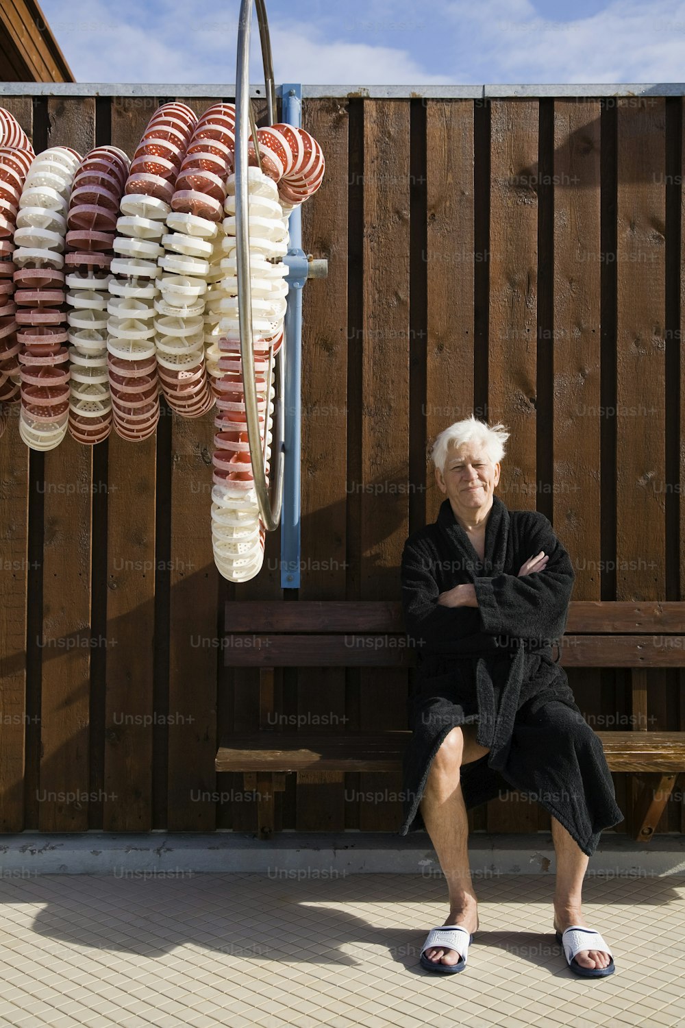 a woman sitting on a wooden bench in front of a wooden fence