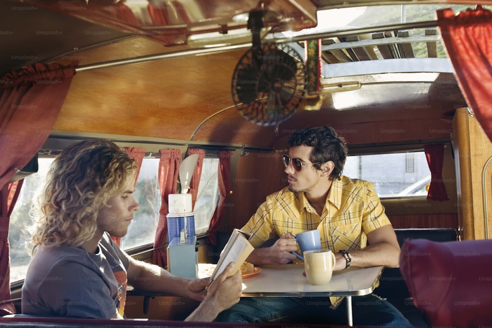 two men sitting at a table in a bus