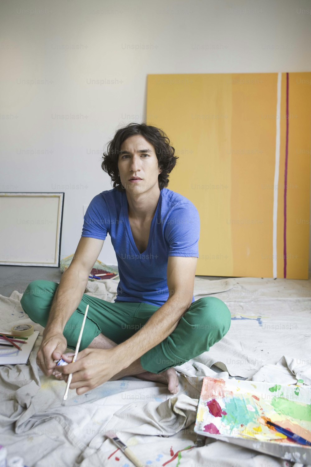 a man sitting on a bed with a paintbrush in his hand