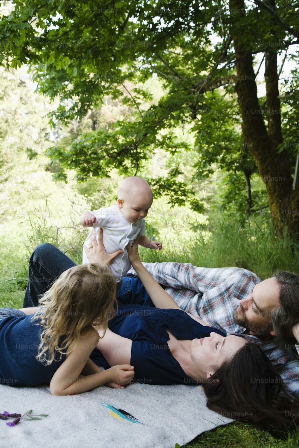 Una famiglia di tre persone sdraiata su una coperta nell'erba