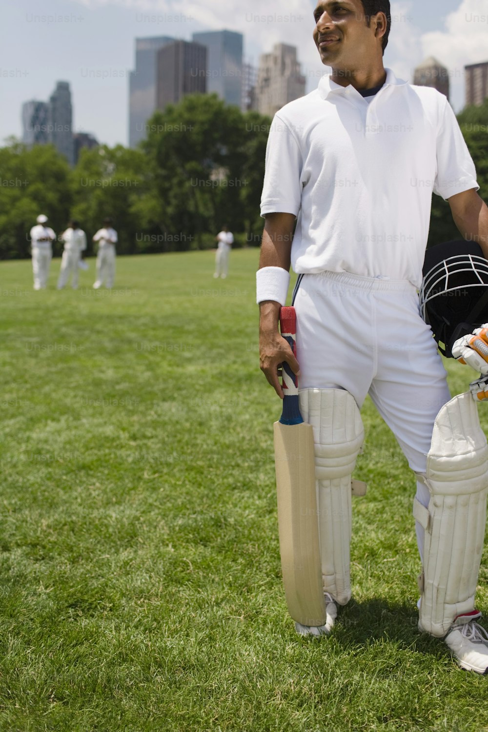 Un hombre sosteniendo un bate de cricket y un casco