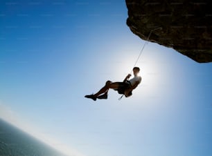 a man hanging on to the side of a cliff