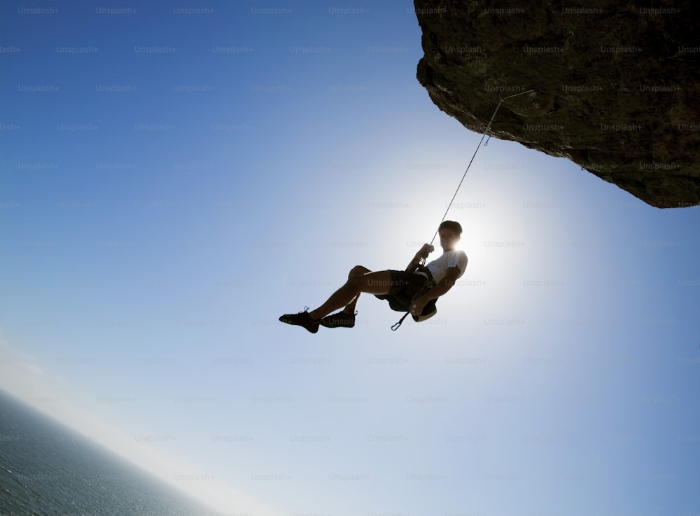 a man hanging on to the side of a cliff