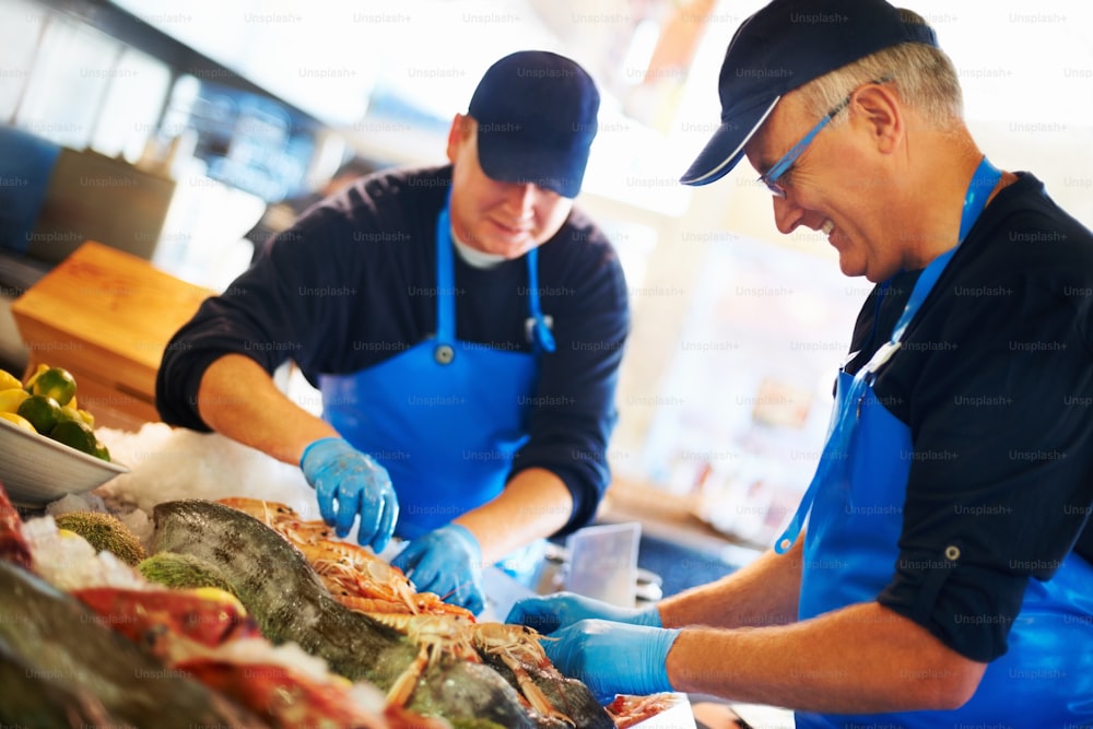 two men in blue aprons are preparing food