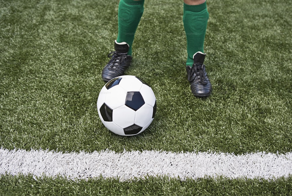 Un jugador de fútbol parado en un campo con una pelota de fútbol