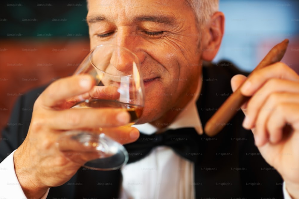 Un uomo in smoking che beve un bicchiere di vino