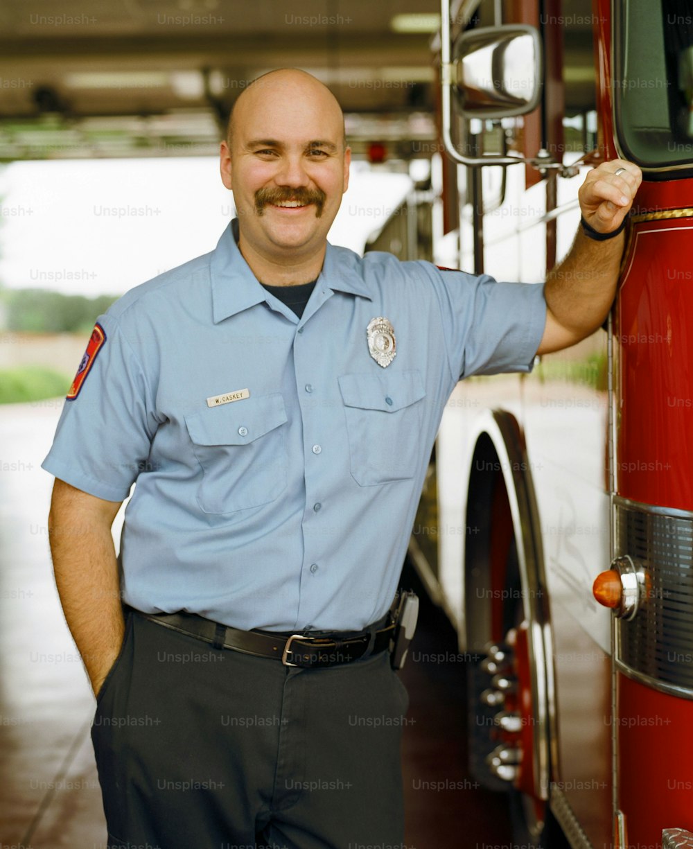 um homem fardado ao lado de um caminhão de bombeiros