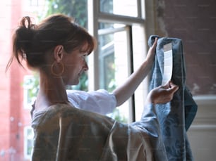a woman opening a curtain to look out a window