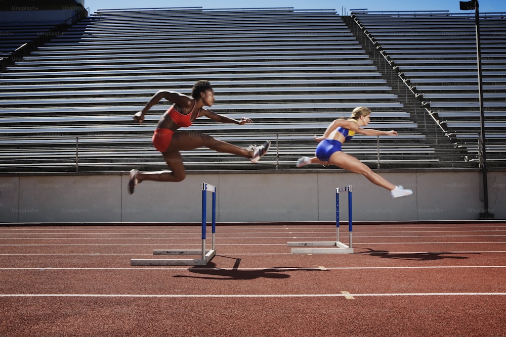 a woman jumping over a hurdle on a track