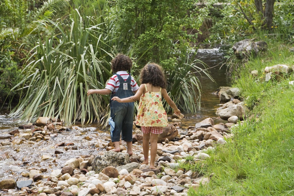 a couple of kids walking across a river