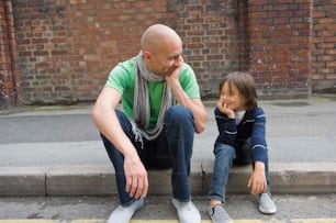 a man and a little girl sitting on a curb