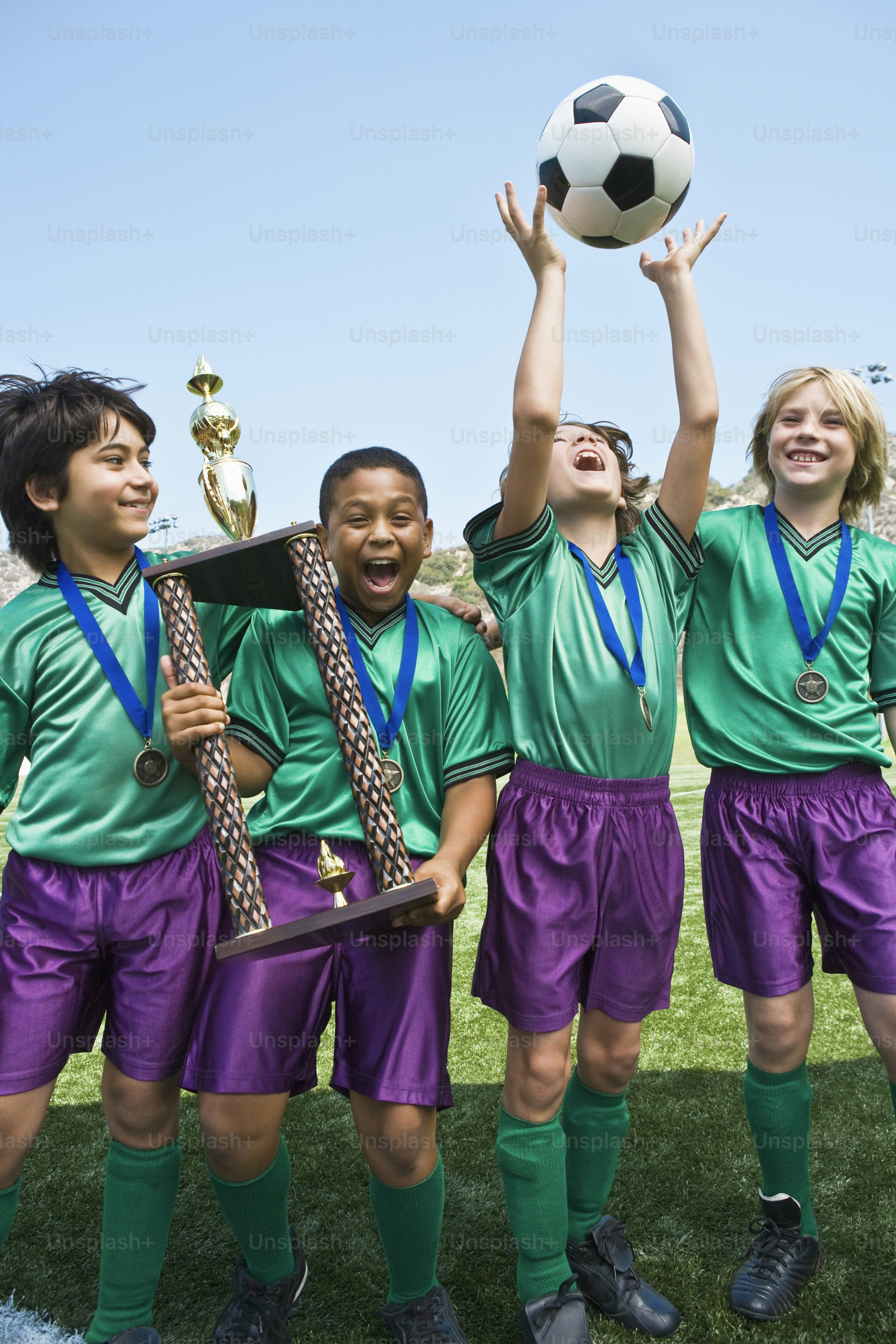 a group of young people standing next to each other holding a soccer ball