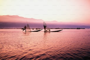 a couple of people standing on top of a boat in the water