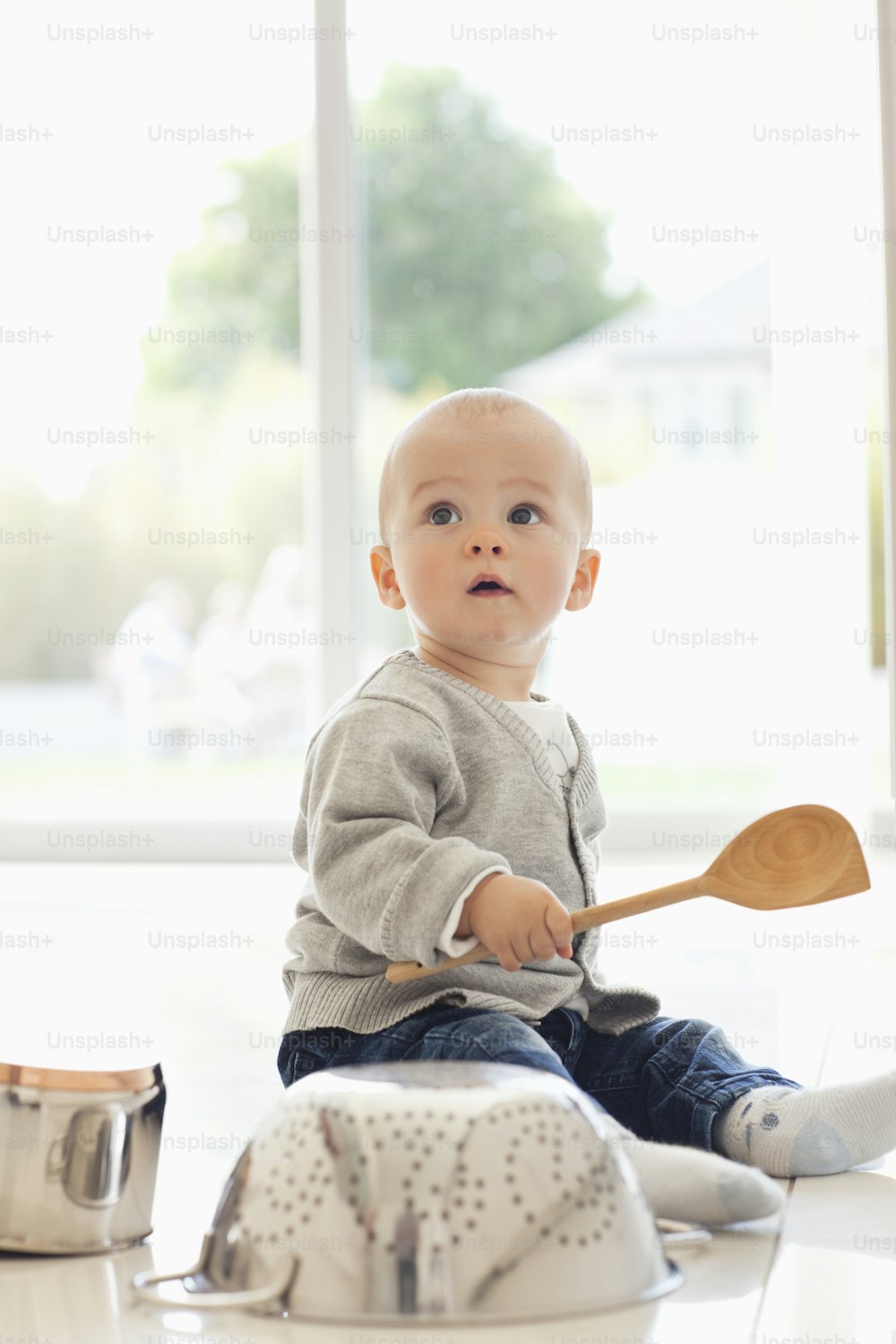 a baby sitting on the floor with a wooden spoon