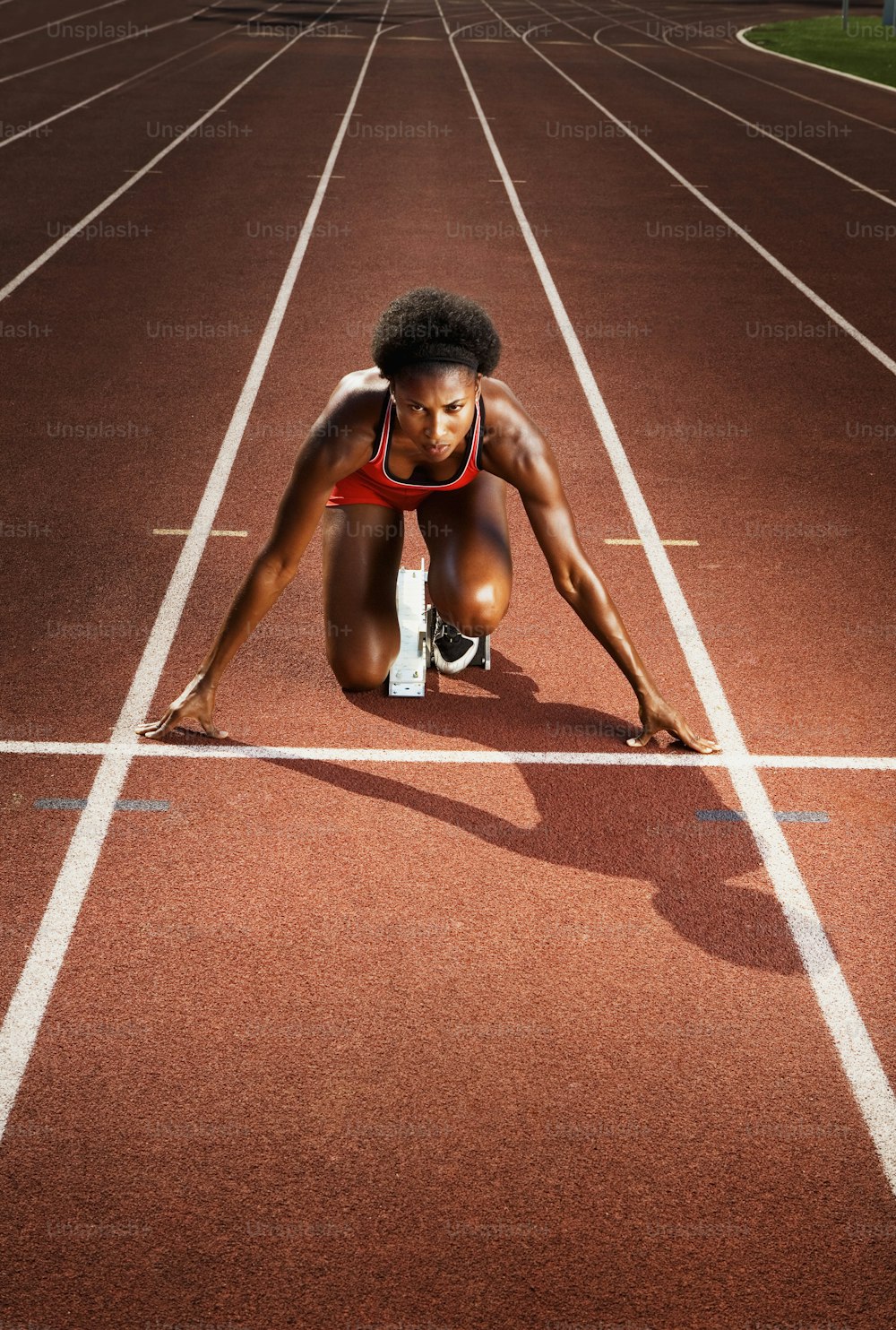 Una mujer arrodillada en una pista de atletismo