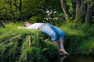 a person laying on the grass next to a body of water