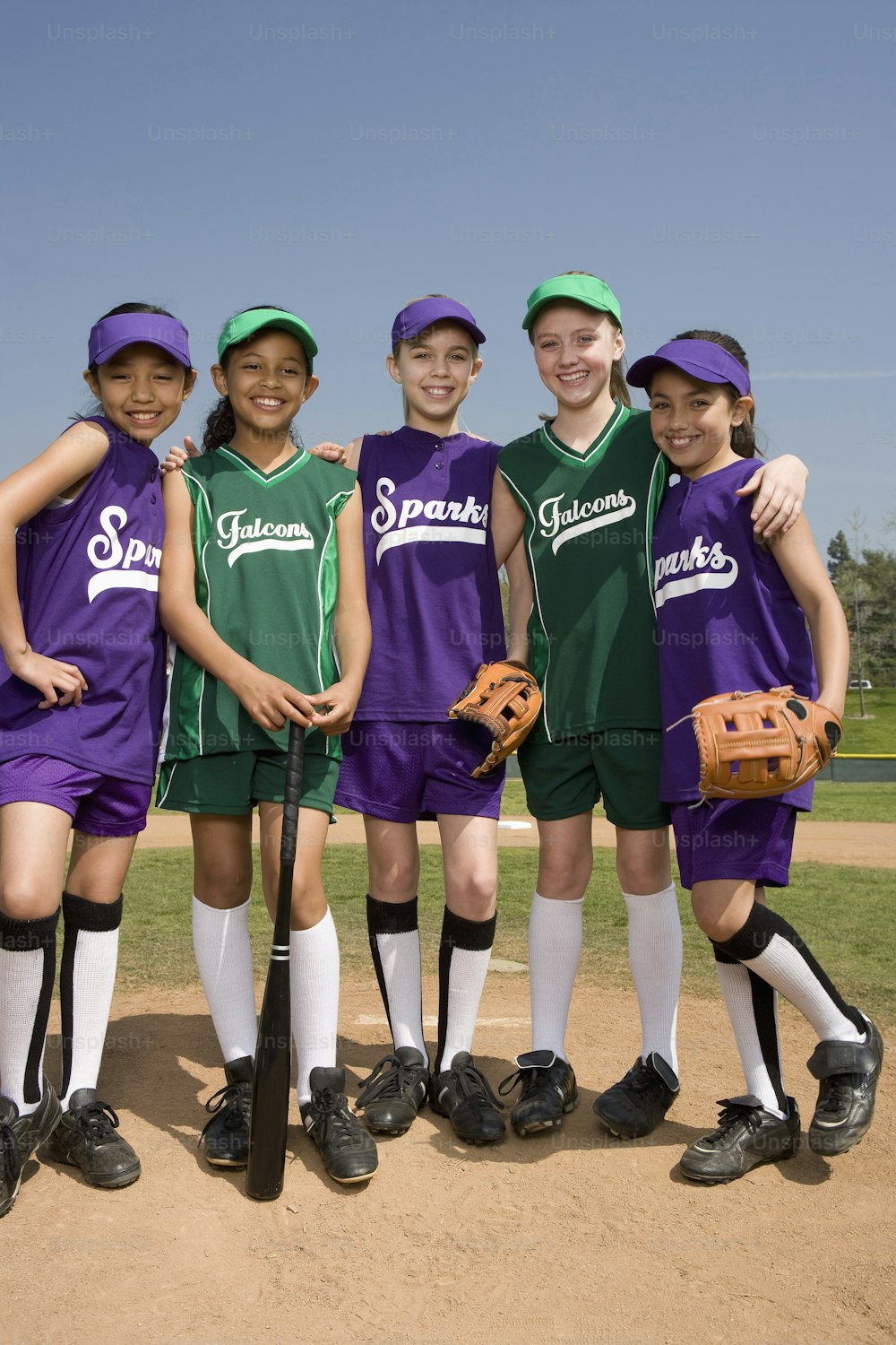 a group of young girls standing next to each other on a baseball field