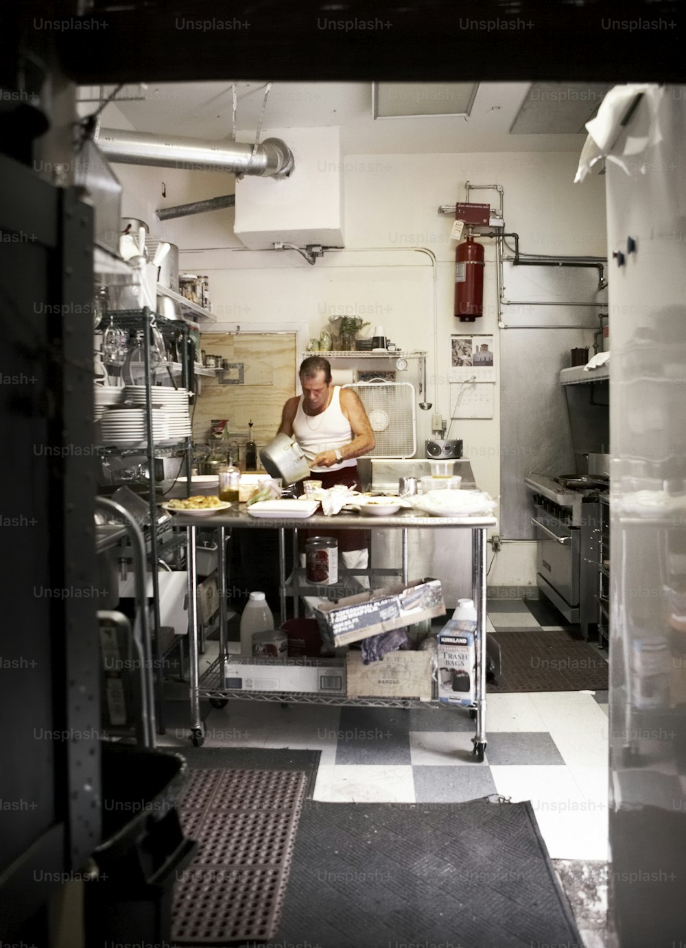 Un hombre trabajando en una cocina con un piso a cuadros