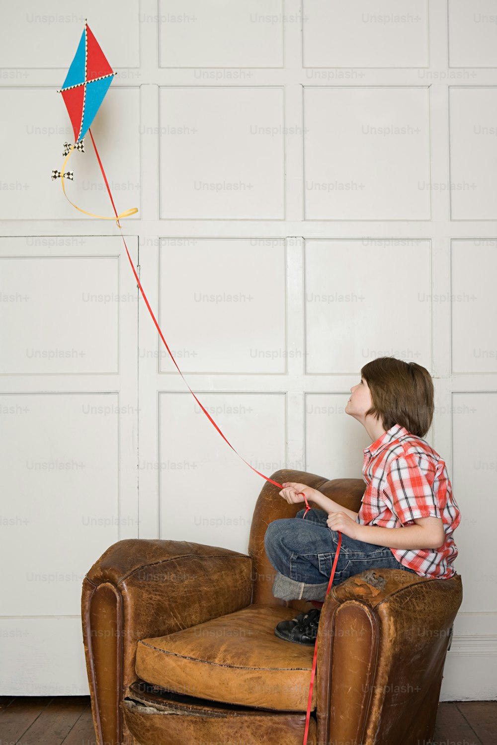 a boy sitting in a chair holding a kite