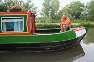 a woman sitting on the side of a green and red boat