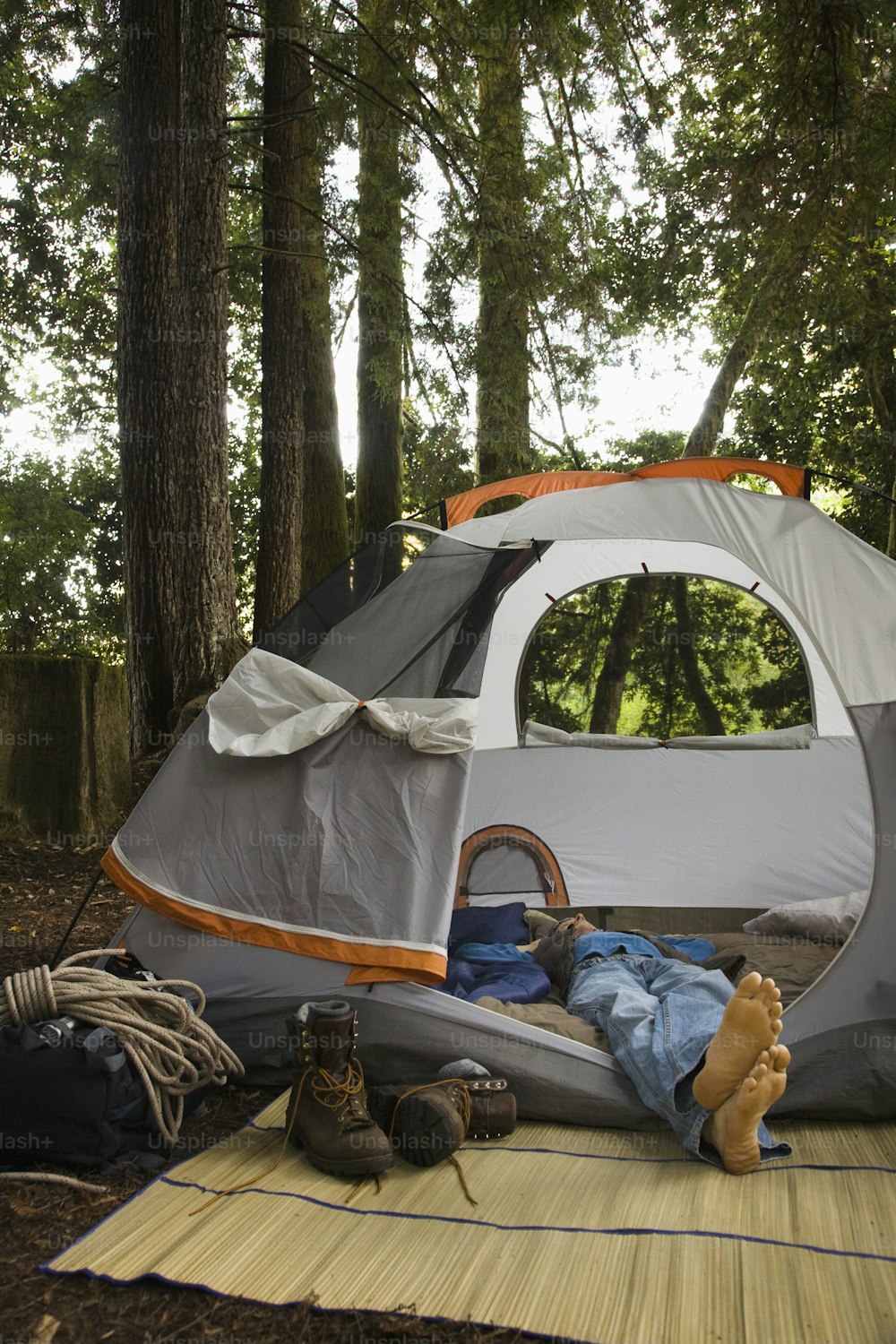 una persona sdraiata su una stuoia davanti a una tenda