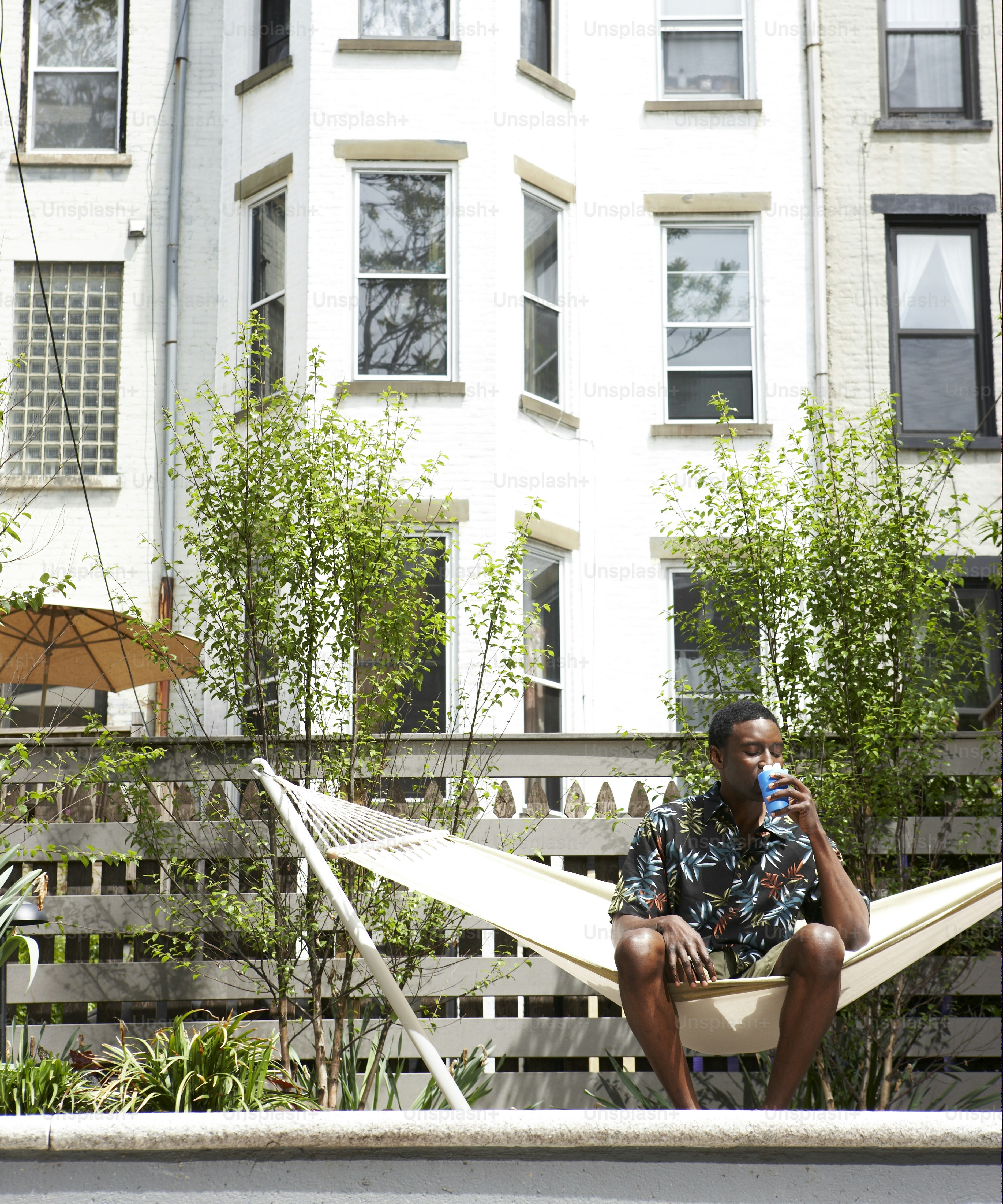 a man sitting in a hammock drinking a beverage