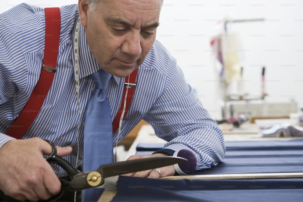 a man cutting a piece of fabric with scissors