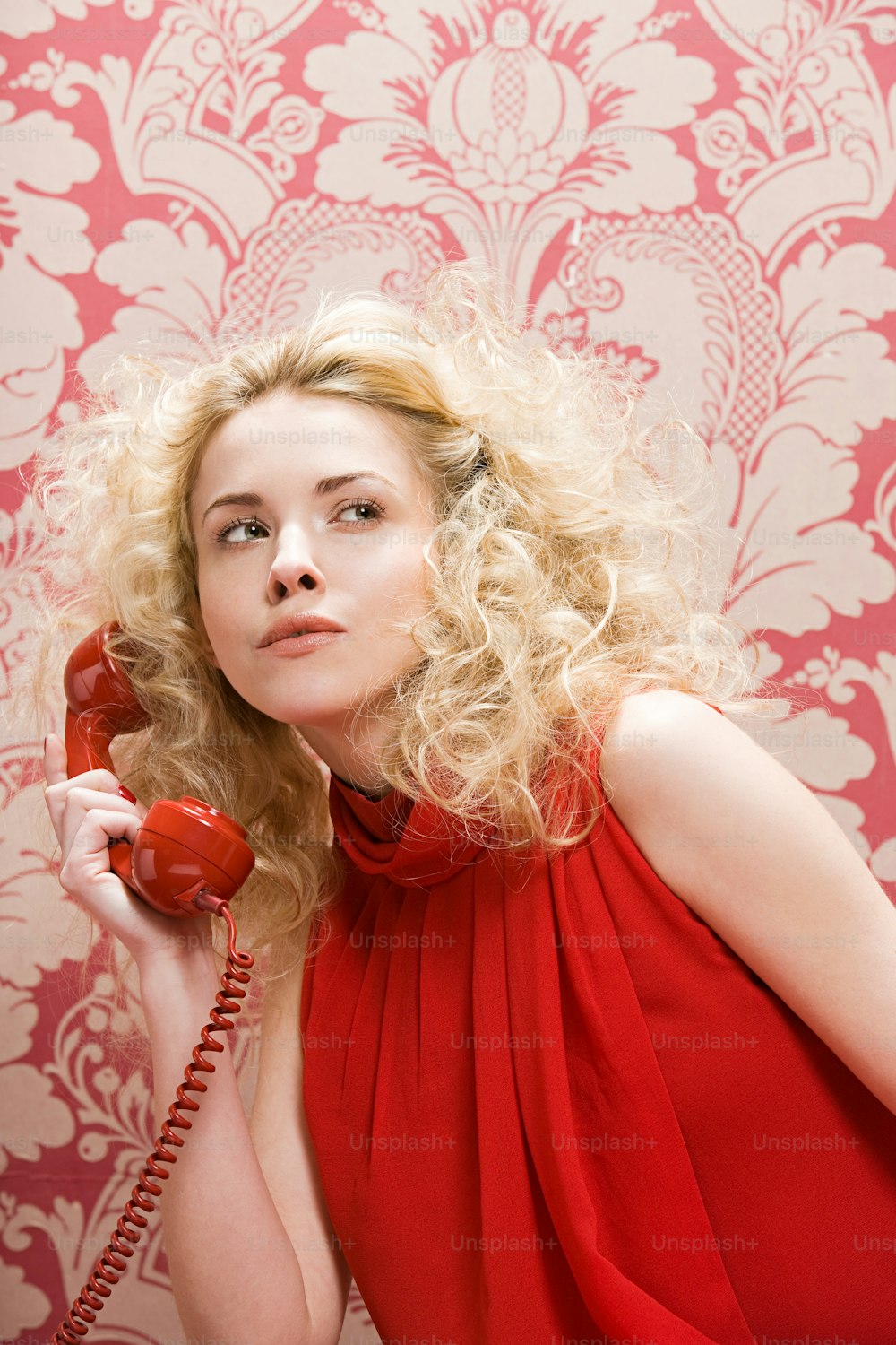 Une femme en robe rouge tenant un téléphone rouge