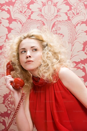 Una donna in un vestito rosso che tiene un telefono rosso
