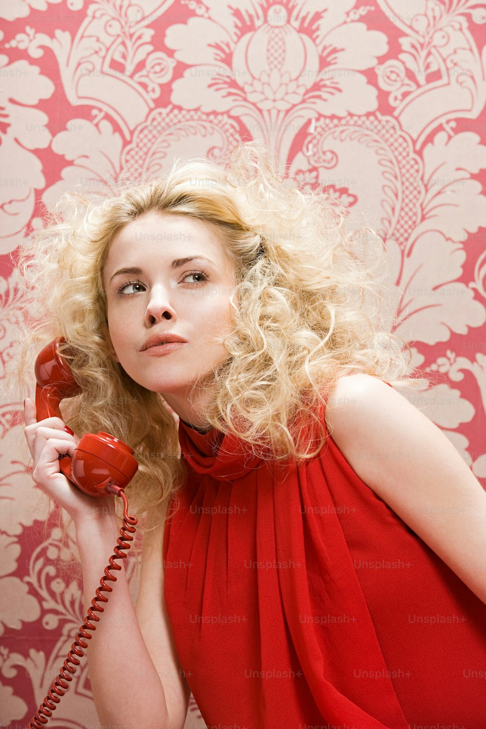 a woman in a red dress holding a red phone