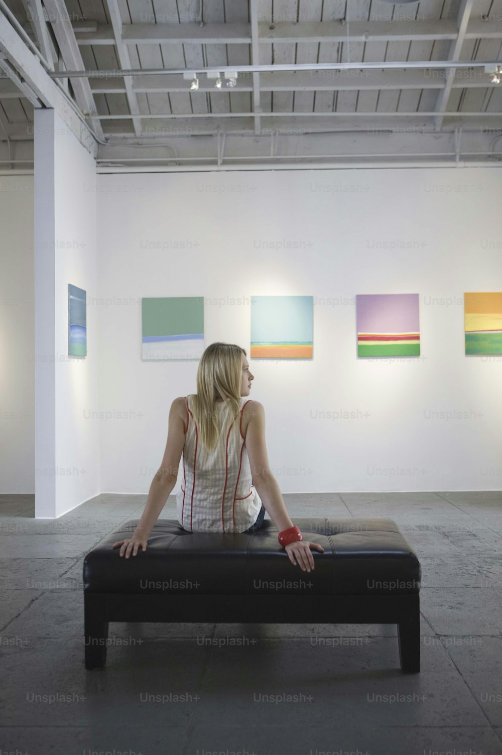 uma mulher sentada em um banco em uma galeria de arte