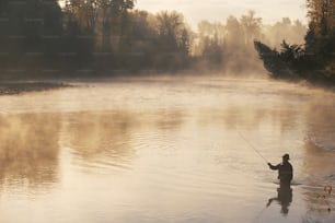 a man standing in a river holding a fishing rod