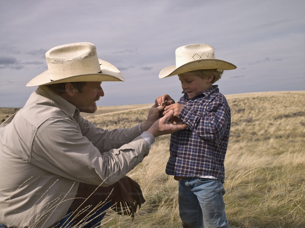 Padre enseñando a su hijo sobre los insectos locales en una propiedad en Big Timber, Montana