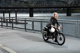 Eine Frau, die mit einem Motorrad über eine Brücke fährt