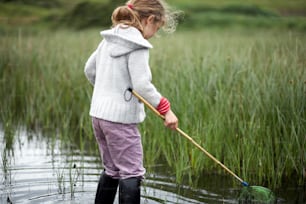 a little girl standing in a body of water holding a net