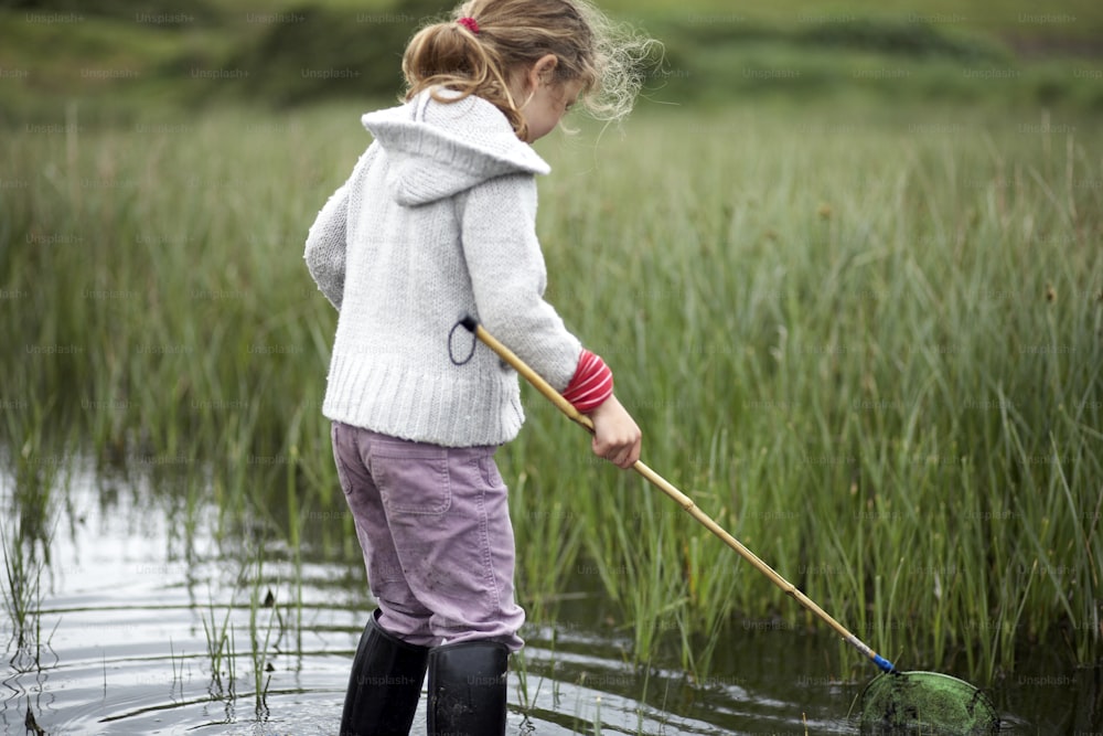 Una niña pequeña parada en un cuerpo de agua sosteniendo una red