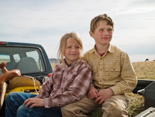 Hermano y hermana en la parte trasera del maletero de una camioneta en Big Timber, Montana
