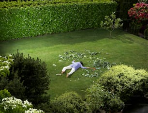 a man laying on the ground in the middle of a yard