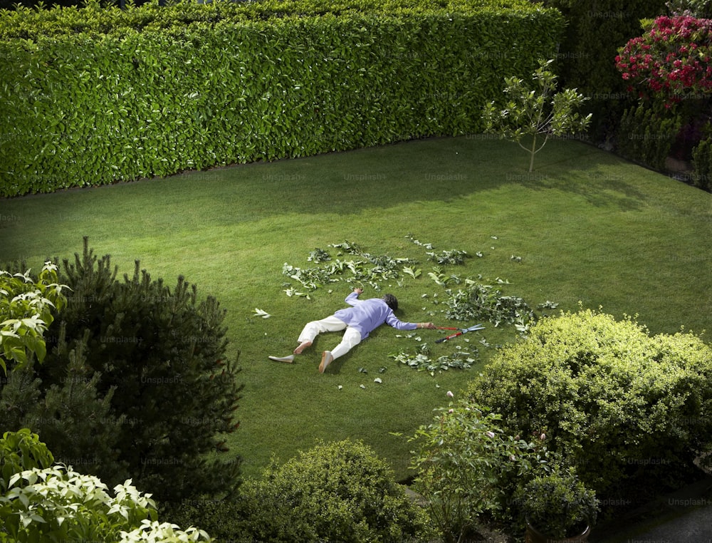 a man laying on the ground in the middle of a yard