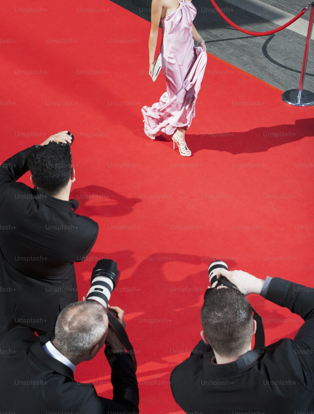 Una mujer con un vestido rosa de pie en una alfombra roja
