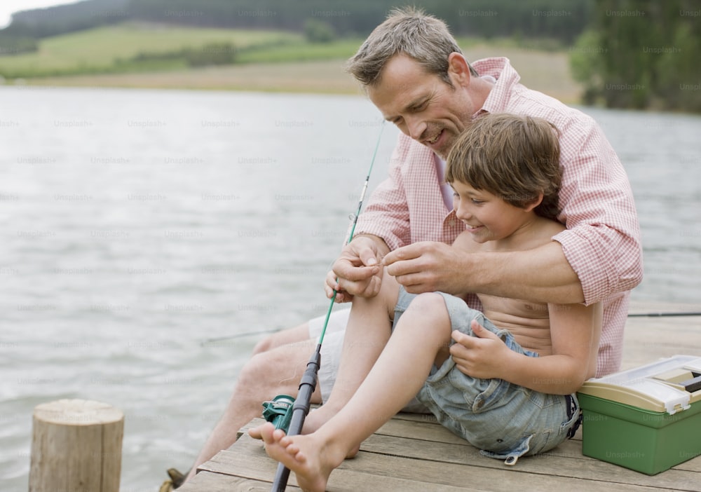 a man and a boy sitting on a dock fishing