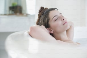 a woman laying in a bathtub with her eyes closed