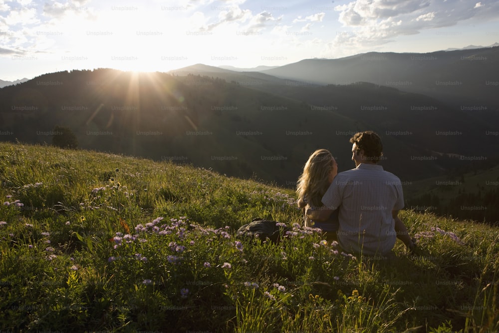 um homem e uma mulher estão sentados em uma colina