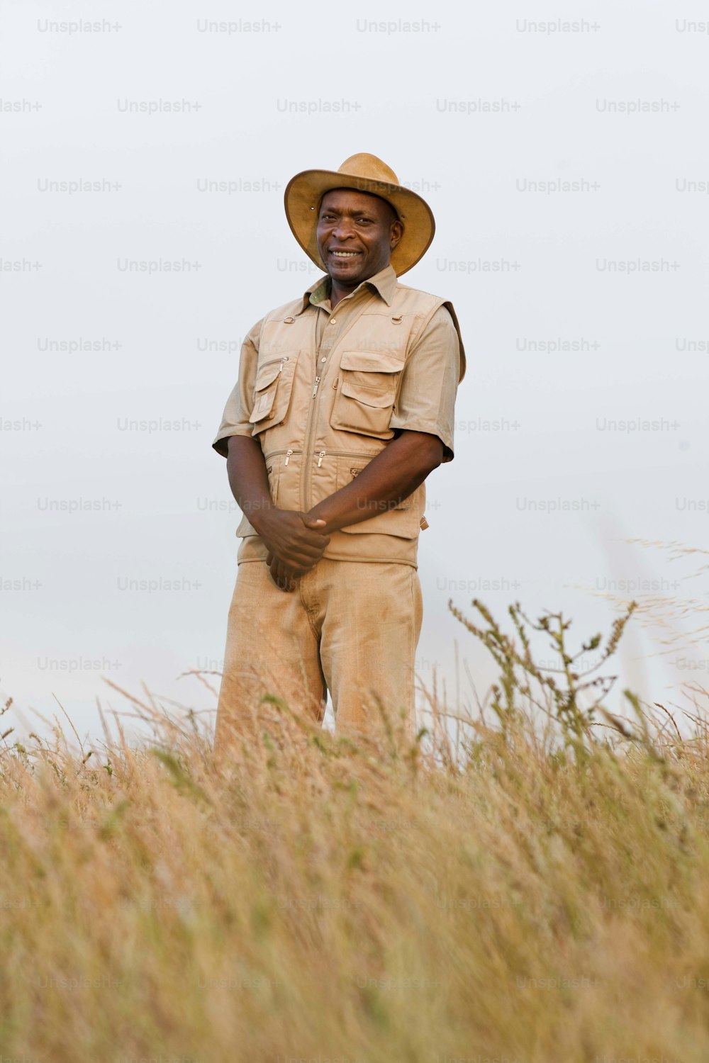 a man standing in a field wearing a hat