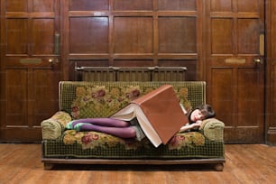 a woman laying on top of a green couch