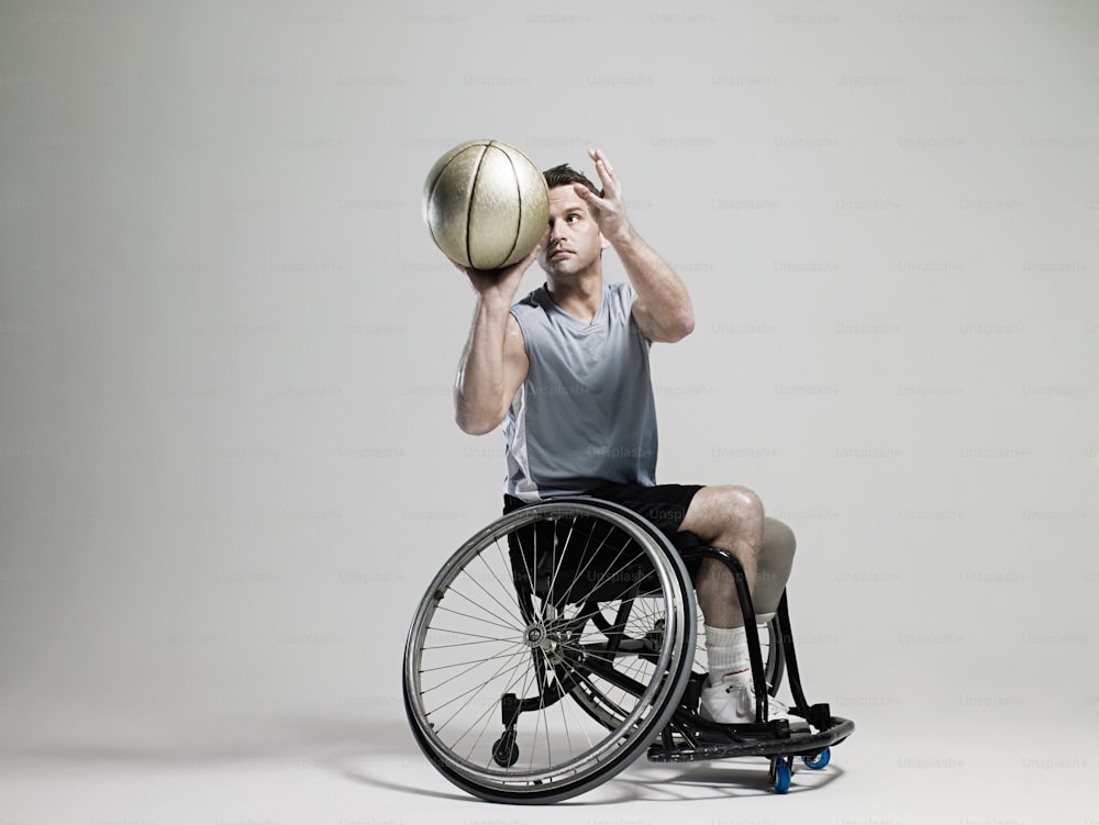 Un hombre en una silla de ruedas sosteniendo una pelota de baloncesto