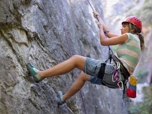 a woman climbing up the side of a cliff